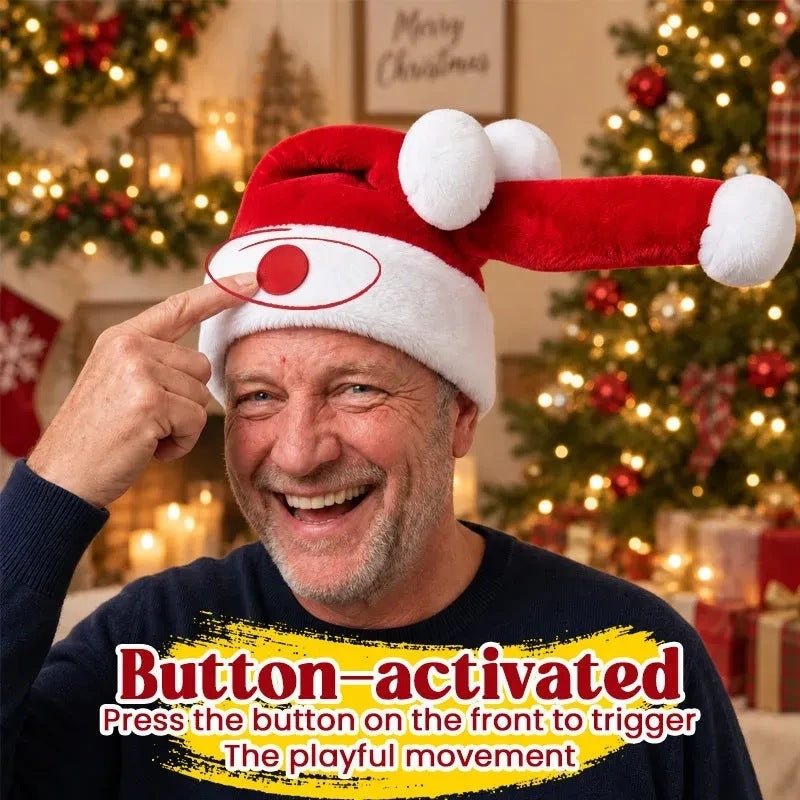 A man smiling broadly while pressing the round button on the front of the hat, the long red tip thrown out sideways to the right, a lit Christmas tree behind him