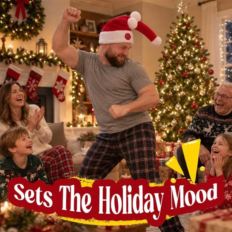 A family in a living room at Christmas: a man in the hat mid-dance with one arm raised while the others around him laugh, a lit tree and a garlanded fireplace behind